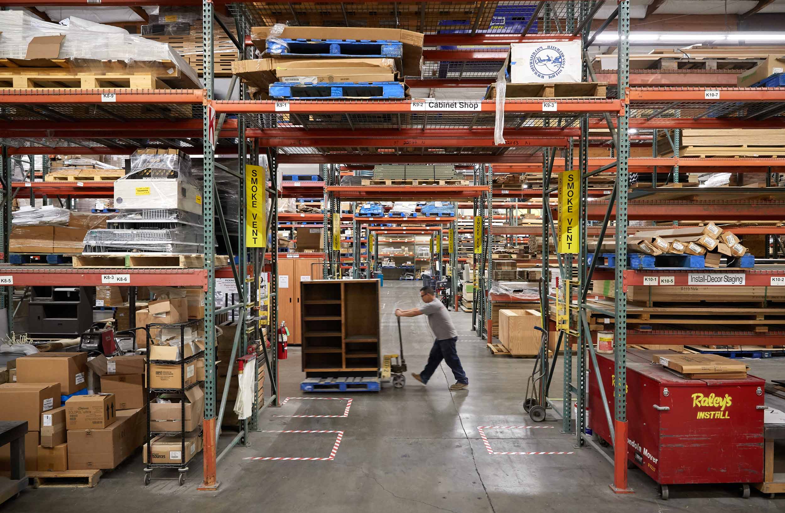A Worker Pushes a Custom Cabinet Through Warehouse